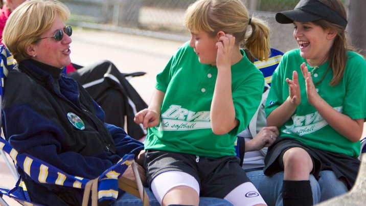 Jennifer and Kelsey watch the Hot Shots bat from their mothers' laps