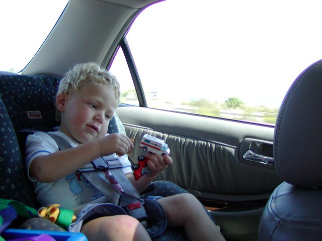 Timothy plays with trucks in the back seat