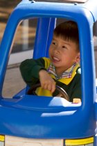 Daniel drives a toy car in the back yard