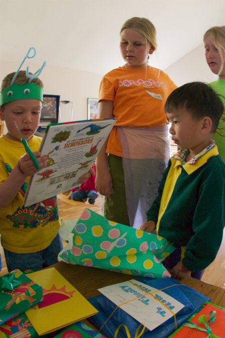 Timothy opens a dinosaur book from Daniel