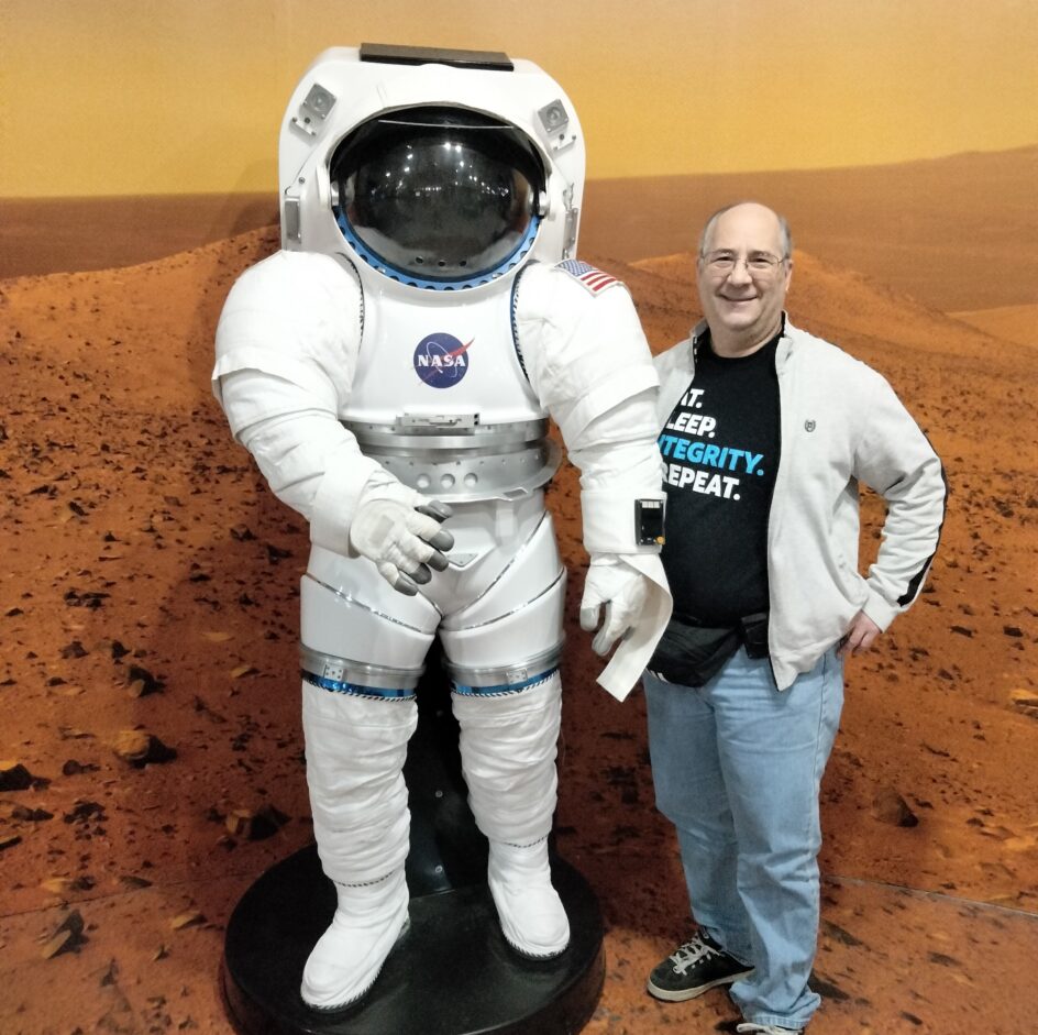Steve Acterman stands “on Mars,” next to a spacesuit.