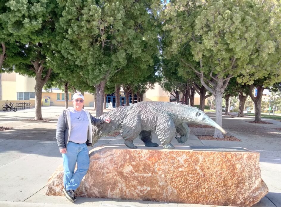 Acterman stands next to a large anteater sculpture.