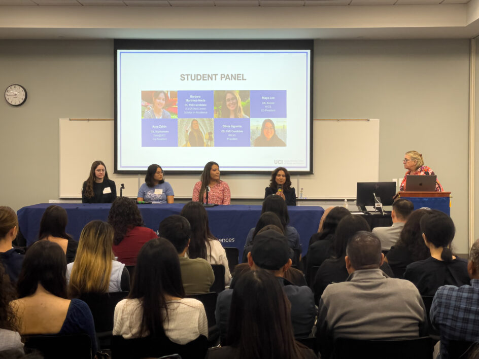 Four UCI students sit at a table in the front of the room, with high school students in the audience.
