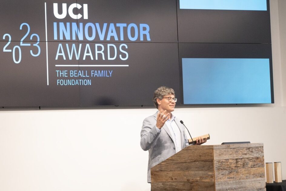 Levorato stands at a podium talking, with “UCI Innovator Awards” on a large screen behind him.