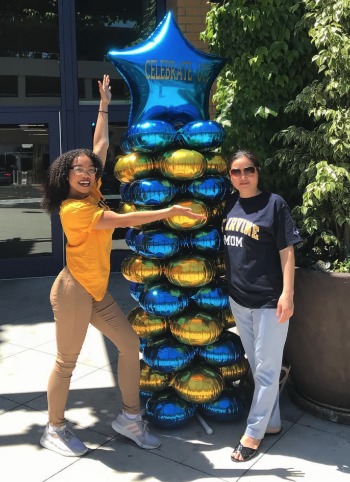 Vitica stands next to a balloon decoration that says “Celebrate UCI,” with her mom, who is wearing a “UC Irvine mom” t-shirt.