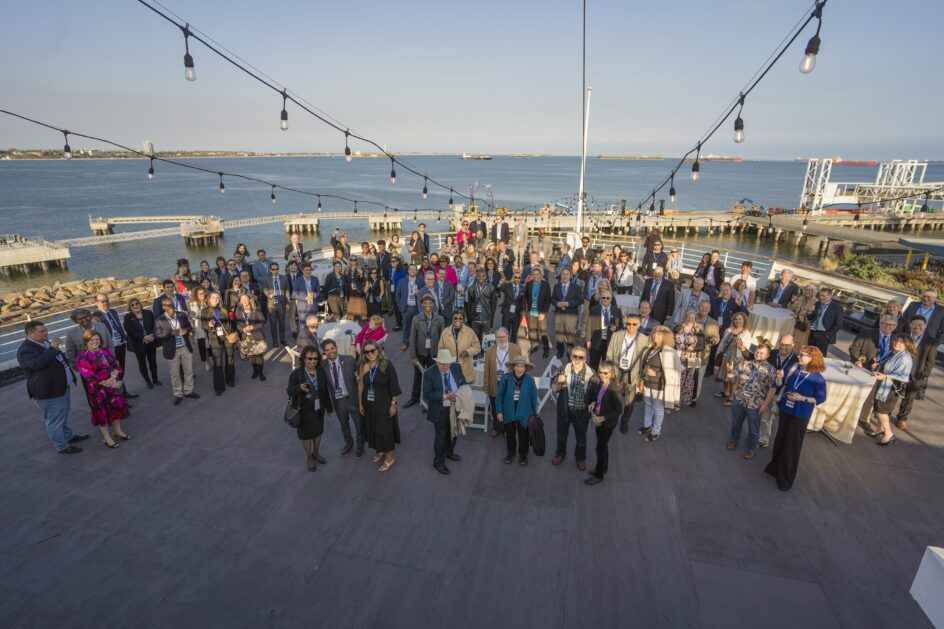 A large group people stand on the front deck of the ship