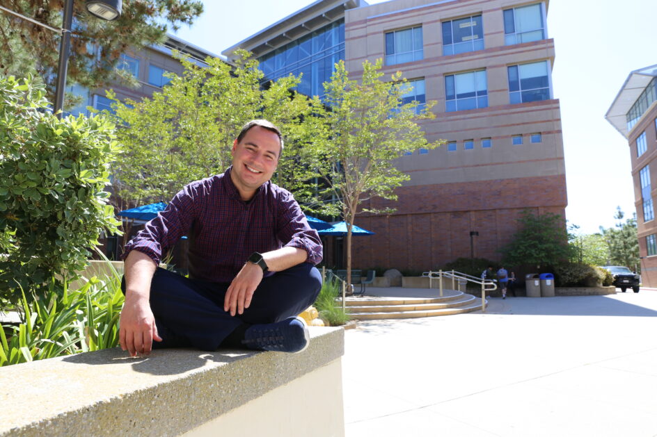 Sergio Gago-Massague sits on a ledge in front of the building.