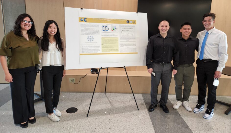 /Vierya stands next to a poster that displays the findings. Two female students stand to the left of the poster, while Vierya and two other male students stand on the left.