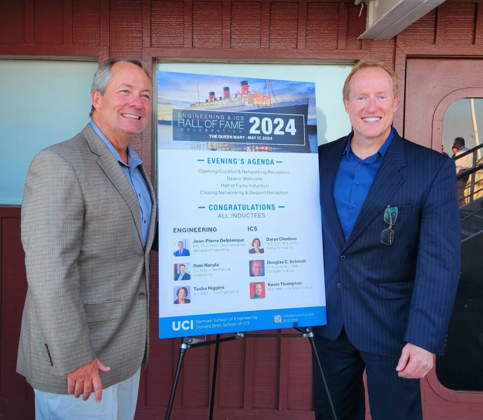 Schmidt and Thompson stand on the ship next to a Hall of Fame 2024 poster.