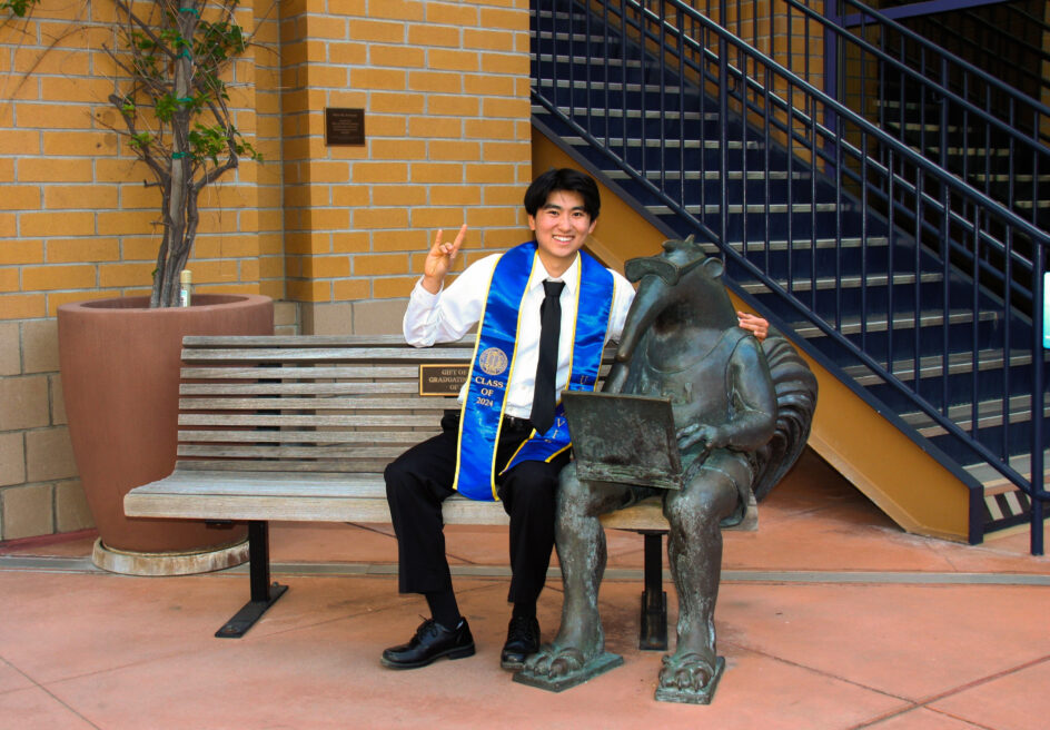 William sits on a bench next to a bronze anteater statue