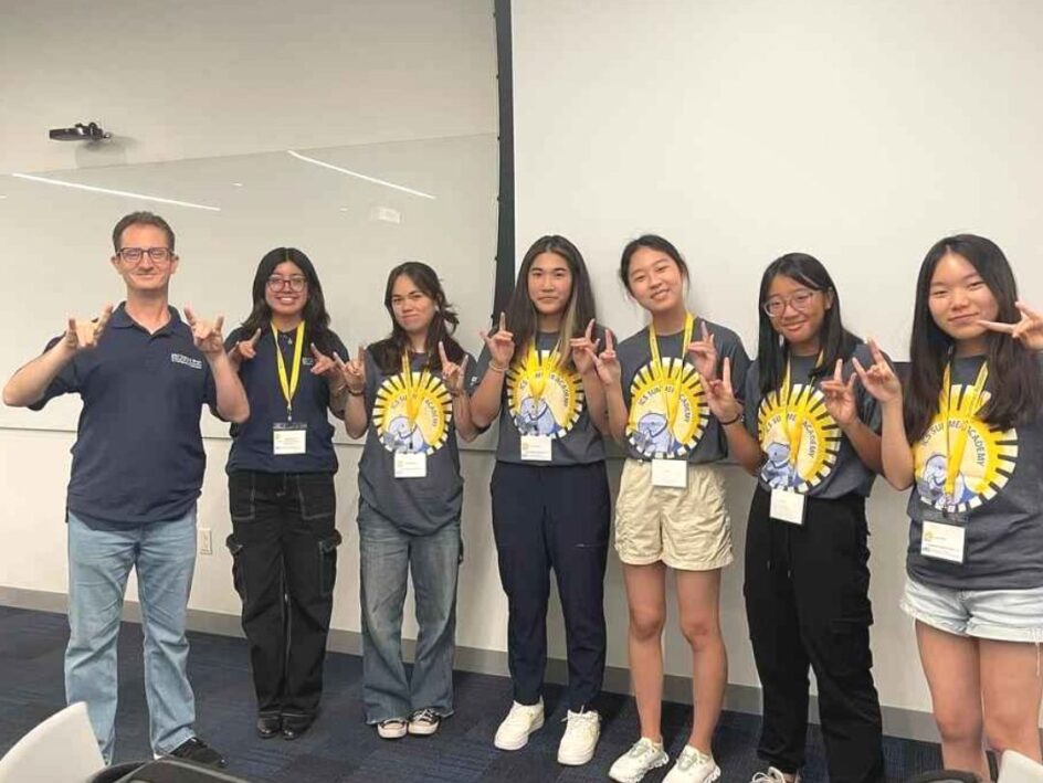 Seven people standing with hands raised for "UCI zot"