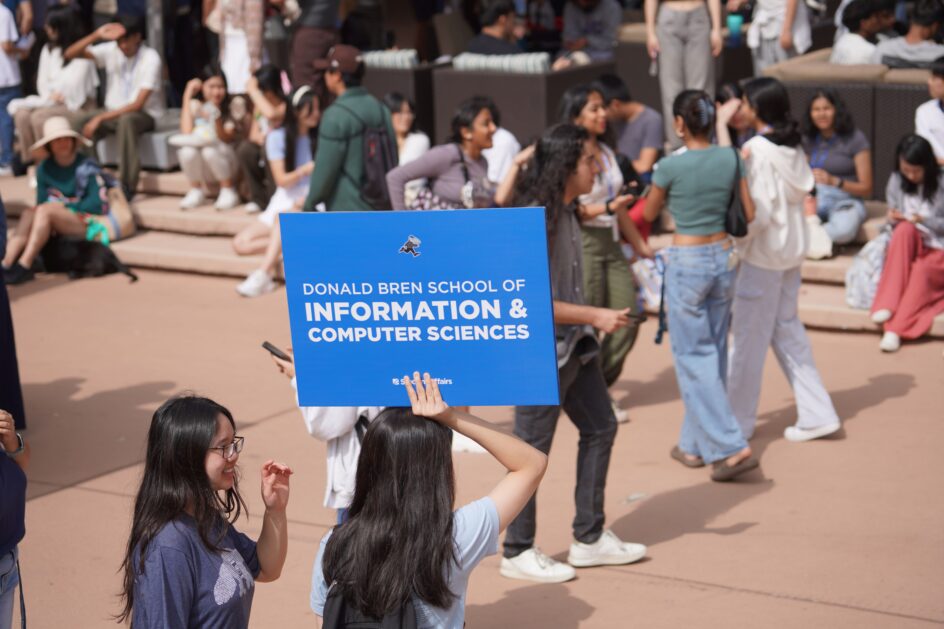 Students gather near someone holding a sign that says Donald Bren School of Information and Computer Sciences