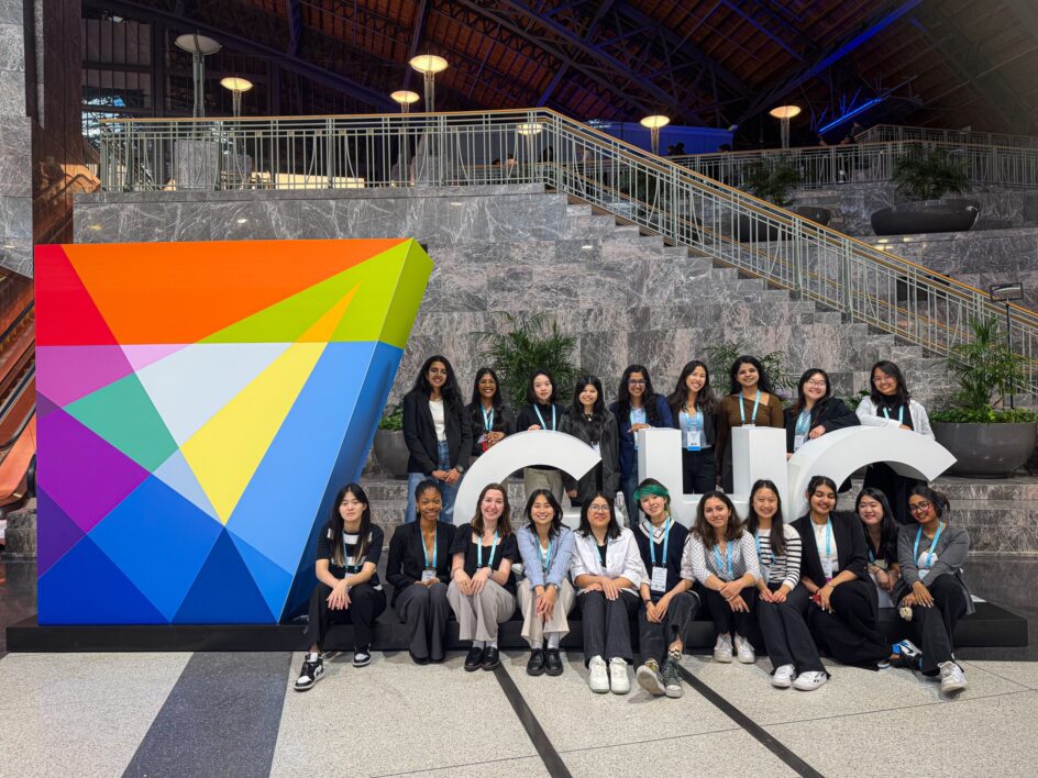 A diverse group of students surrounding a large sign that says GHC.