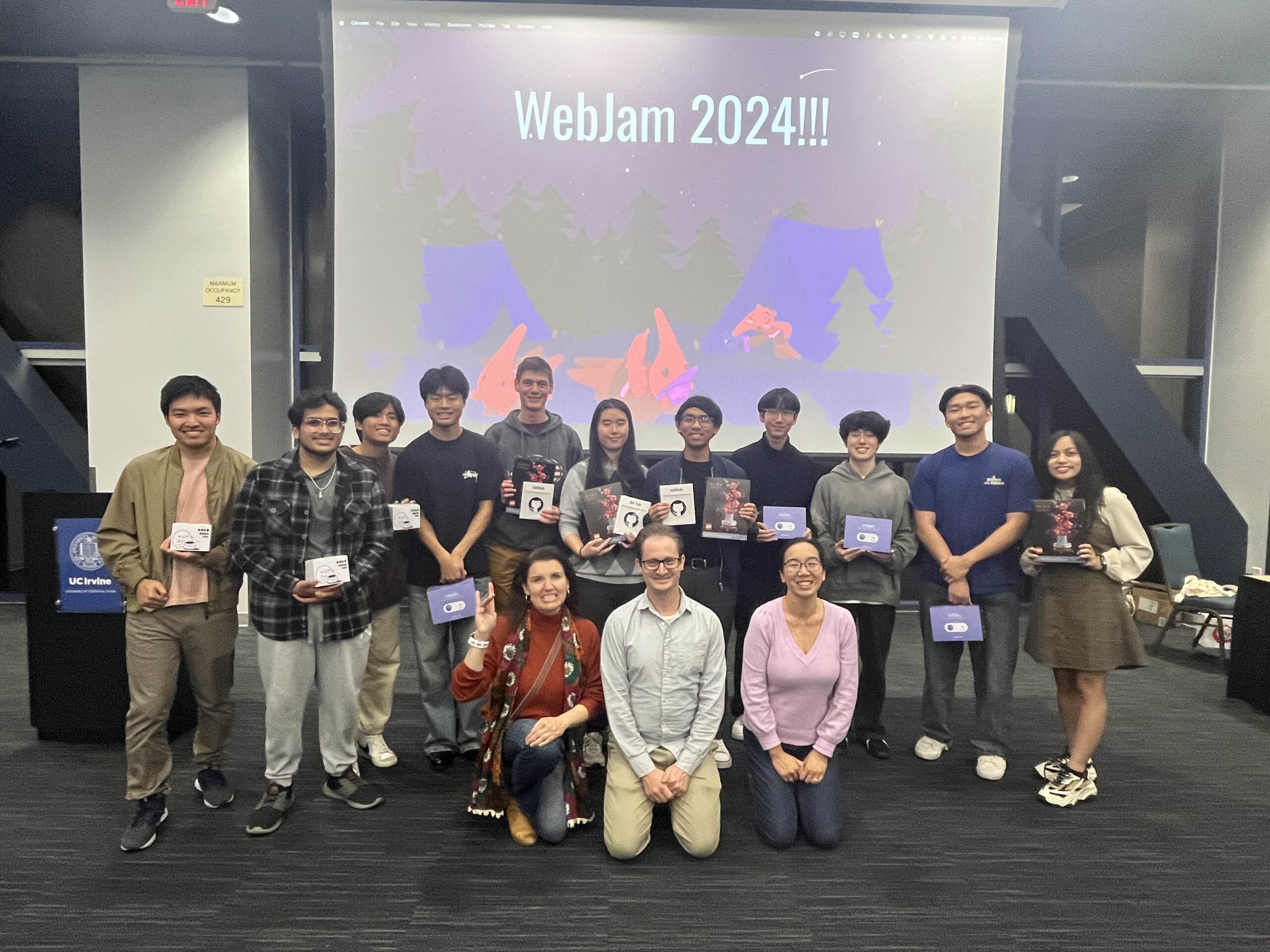 A group of students and professors in front of a screen that says WebJam 2024.